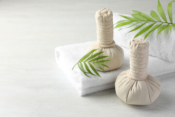 Spa composition. Herbal bags, towels and palm leaves on light table, space for text