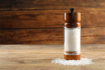 Salt shaker on wooden table, space for text