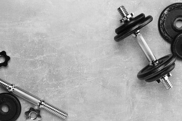 Barbell and parts of one on grey textured background, flat lay. Space for text