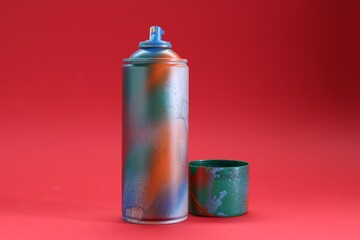 One can of bright spray paint with cap on red background