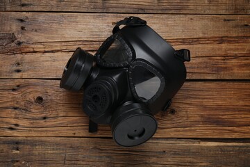 One gas mask on wooden table, top view