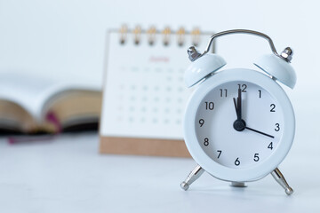 Alarm clock with calendar and holy bible book on white. Close-up. Christian biblical concept of...