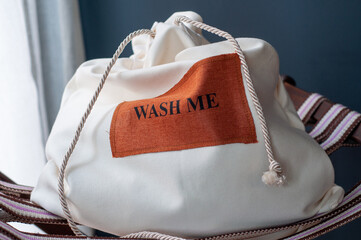 Naklejka premium white laundry bag on chair with dark background with text 'wash me'