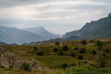A mountain range with a cloudy sky in the background. The sky is overcast and the mountains are...