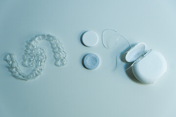 Transparent aligners next to a dental floss, retainer cleaning tablets and dental floss on the...