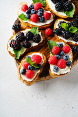 Sweet berries bruschetta with strawberry, raspberry, blueberry on wooden cut board