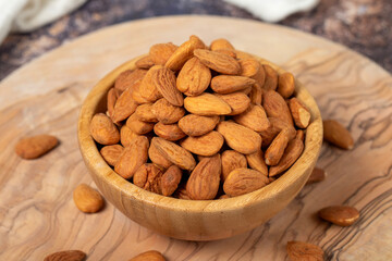 Almonds on wood background. Roasted almonds in a bowl. Close up
