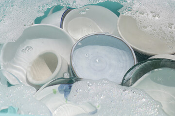 Dishes and bowls in water and bubbles of dishwashing liquid