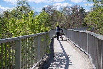 Man pushing a bicycle crossing the bridge