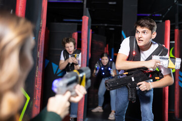 Portrait of young man with laser gun having fun with family on laser tag arena