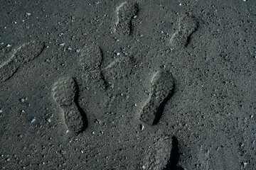Footprints on black sand on the beach