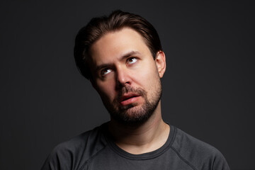 Young tired man portrait on dark background