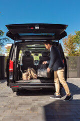 Stylish bearded man in smart casual wear with luggage going by car on vacation