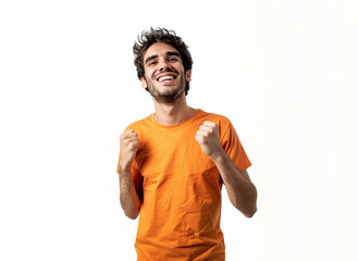 20s hispanic man celebrating with raised fists, wearing orange t-shirt, he is isolated on white background. 
