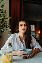 One young caucasian woman is eating corn flex breakfast at home before work	