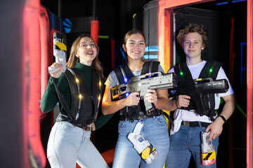 Fototapeta premium Three people with lasertag guns standing in lasertag arena