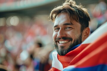 Handsome male sports fan smiling and cheering with national flag