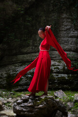 Asian girl in a beautiful red kimono in the middle of nature in a canyon