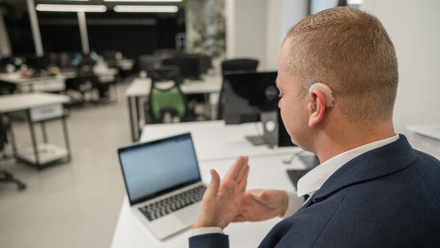 Caucasian deaf man communicates in sign language on laptop in office. 