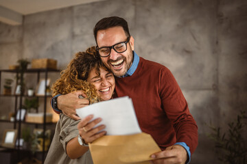 Happy couple read the good news in the post envelope letter and hug