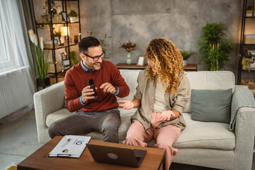 Man use mobile phone while woman work from home on laptop