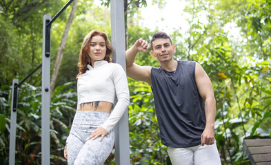 couple with sports clothes posing for the camera in a daytime park with nature background in high resolution