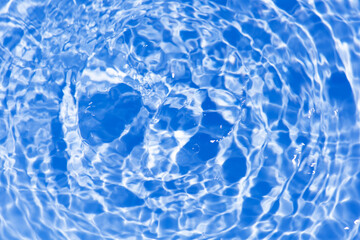 Blue water with ripples on the surface. Defocus blurred transparent blue colored clear calm water surface texture with splashes and bubbles. Water waves with shining pattern texture background.