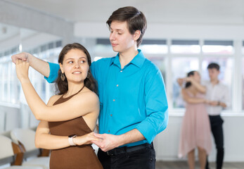 Young man and young woman dance ballroom dance waltz in studio