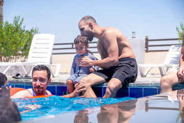 Relatives of different ages are enjoying themselves in the swimming pool, having a great time together and supporting each other to make the most of their vacation