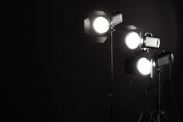 Dark photo background and professional lighting equipment in studio. Space for text