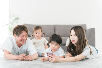 家のリビングでスマホを見る笑顔の日本人家族（動画・ファミリー）
