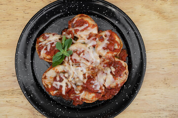 Stuffed pasta. Top view of sorrentinos with a mediterranean tomato sauce and provolone cheese in a black dish on the wooden table.