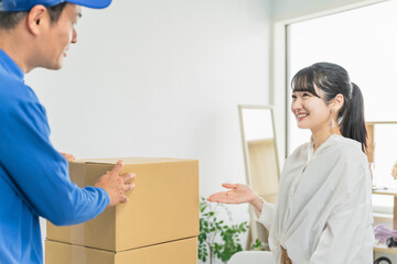 宅配・配送の荷物の集荷をお願いする女性客と配送員・配達員の男性
