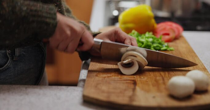 Hands, knife and cutting vegetables for cooking in kitchen or meal prep on wooden board, mushrooms or vegetarian. Person, chopping and home recipe for healthy nutrition with lunch, dinner or wellness