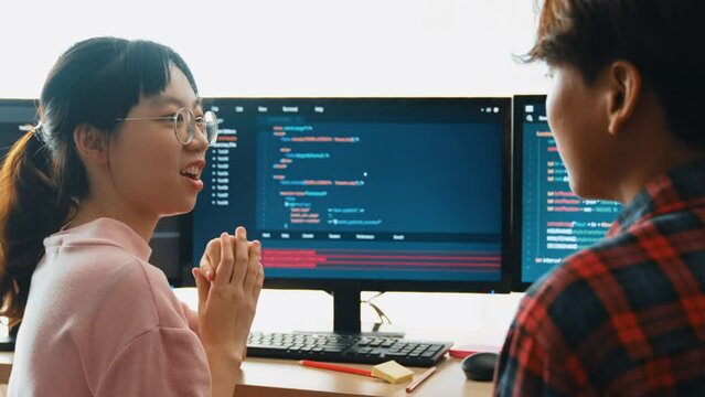 Slow motion back end software developer engineer for computer programming working together on debugging writing computing code, solving complex algorithms display on monitor in office. Burgeoning