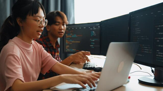Slow motion back end software developer engineer for computer programming working together on debugging writing computing code, solving complex algorithms display on monitor in office. Burgeoning