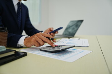 professional businessman is sitting in his office, confidently smiling while working on his laptop. A successful entrepreneur and leader, he embodies corporate success and happiness