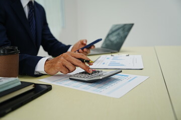 professional businessman is sitting in his office, confidently smiling while working on his laptop. A successful entrepreneur and leader, he embodies corporate success and happiness