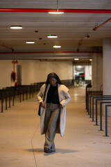 A confident young woman elegantly walking through a modern indoor setting, proudly displaying her chic outfit