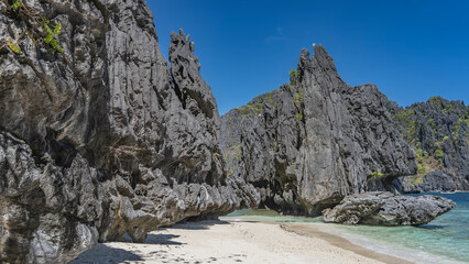 Picturesque karst rocks on the shore of the turquoise bay. There is green tropical vegetation on...
