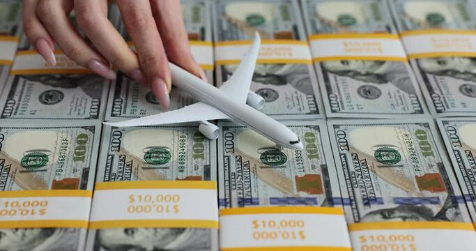 Woman places toy plane onto packs of hundred dollar bills