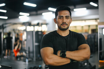 Portrait of muscular man standing confidently at sport club gym. Healthy lifestyle concept.