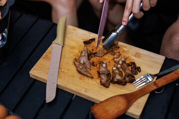 close up woman hands use a knife to cuting the grill meat streak in camp ground,