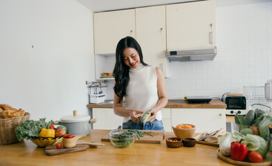 Woman Preparing Fresh Vegetables in a Modern Kitchen with White Cabinets and Wooden Countertops
