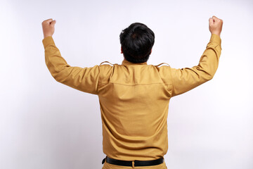 Excited male indonesian government employees worker wearing brown uniform raised his arm. Back view