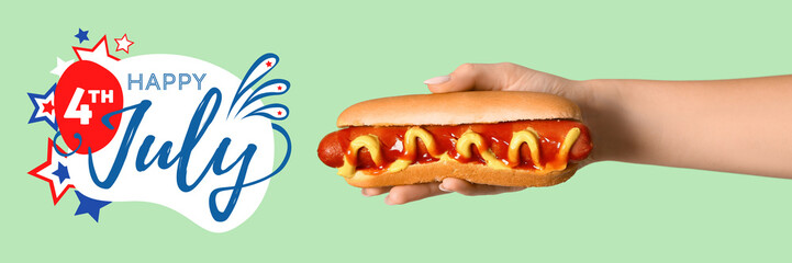 Woman holding tasty hot dog on green background