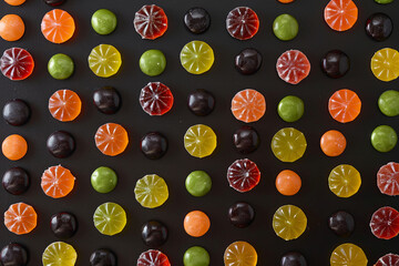 Top view of a colorful assortment of delicious candies arranged on a black background, creating an appetizing and visually appealing image