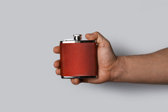 Man holding hip flask on grey background