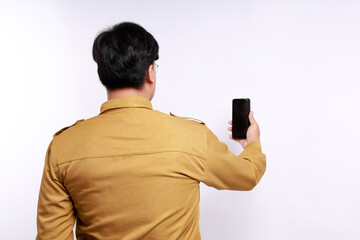 Back view of Indonesian government worker holding cell phone with blank display