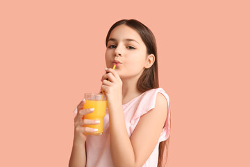 Little girl drinking orange juice on pink background